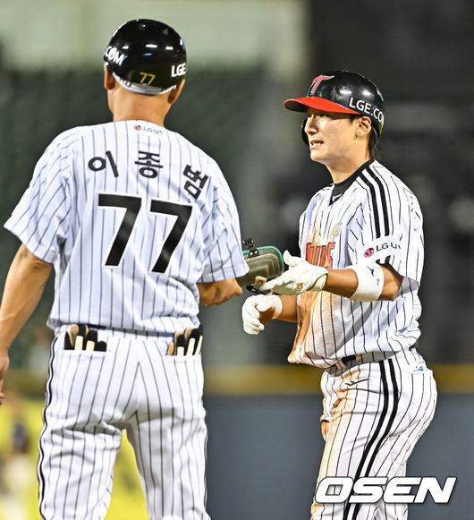 7회말 1사 LG 신민재가 내야안타를 날리고 이종범 1루 코치에게 장비를 전달하고 있다.