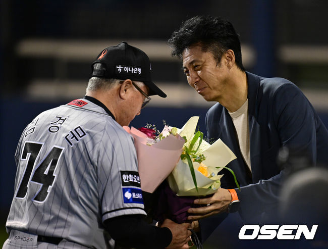 [OSEN=잠실, 김성락 기자] 명장이 돌아왔다. 프로야구 한화 이글스 김경문 감독이 4번의 도전 끝 사령탑 통산 900승 대업을 달성했다. 한화 이글스는 11일 서울 잠실구장에서 열린 2024 신한 SOL뱅크 KBO리그 두산 베어스와의 시즌 7차전에서 6-1로 승리했다. 경기 종료 후 한화 손혁 단장이 김경문 감독에게 꽃다발을 전달하고 있다. 2024.06.11 / ksl0919@osen.co.kr