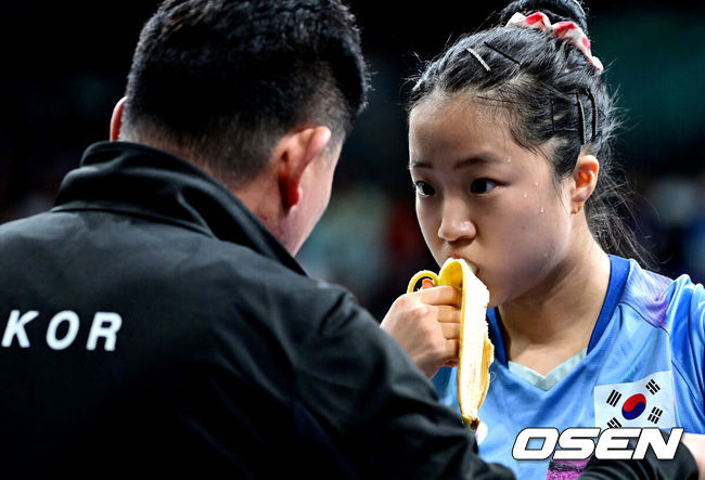 [OSEN=파리(프랑스), 최규한 기자] 1일 (한국시간) 프랑스 파리 사우스 파리 아레나 4에서 ‘2024 파리올림픽’ 탁구 여자 단식 8강 한국 신유빈과 일본 히라노 미우의 경기가 열렸다. 신유빈은 히라노를 상대로 7게임까지 가는 접전 끝에 4-3으로 이겼다. 신유빈은 3게임까지 가져오며 상승세를 이어갔다. 하지만 히라노의 기세도 만만치 않았다. 4게임부터 3게임 연속 상대를 압도했다. 7게임 들어 손에 땀을 쥐게 하는 접전 끝에 마지막에 웃었다. 신유빈이 작전 타임 때 바나나를 먹으며 오광헌 감독과 대화를 나누고 있다. 2024.08.01 / dreamer@osen.co.kr