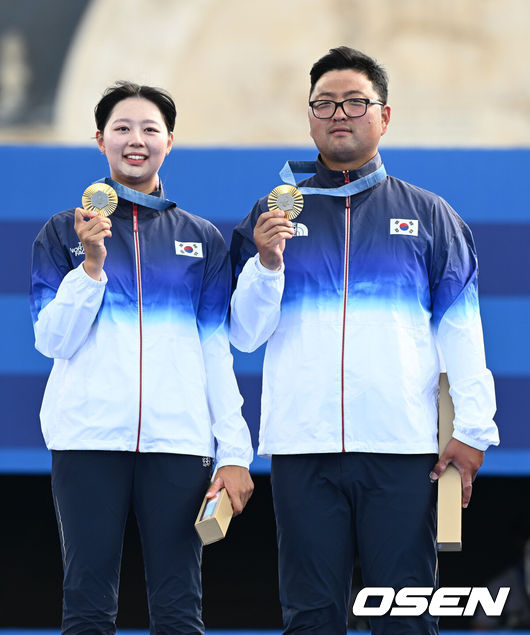 [OSEN=파리(프랑스), 최규한 기자] 이번에도 한국 양궁은 무적이었다. 임시현(21, 한국체대)과 김우진(32, 청주시청)이 남녀 단체전에 이어 혼성 단체전에서도 시상대 가장 높은 곳에 서면서 '동반 2관왕'을 달성했다. 한국 양궁의 올림픽 2연패도 달성했다.임시현과 김우진은 2일(한국시간) 프랑스 파리 앵발리드에서 열린 2024 파리 올림픽 양궁 혼성단체전 결승전에서 미셸 크로펜-플로리안 운루(독일)를 6-0(38-35 36-35 36-35)로 꺾고 금메달을 목에 걸었다.금메달을 따낸 한국 임시현과 김우진이 시상대에서 포즈를 취하고 있다. 2024.08.02 / dreamer@osen.co.kr