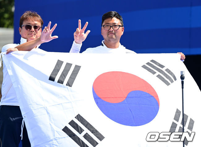 [OSEN=파리(프랑스), 최규한 기자] 4일(한국시간) 프랑스 파리 레쟁발리드에서 ‘2024 파리올림픽’ 양궁 남자 리커브 개인 금메달결정전 한국 김우진과 미국 브래들리 엘리슨의 경기가 열렸다.김우진은 마지막 슛오프 끝에 금메달을 거머쥐었다.김우진이 박성수 감독과 함게 태극기를 들고 포즈를 취하고 있다. 2024.08.04 / dreamer@osen.co.kr