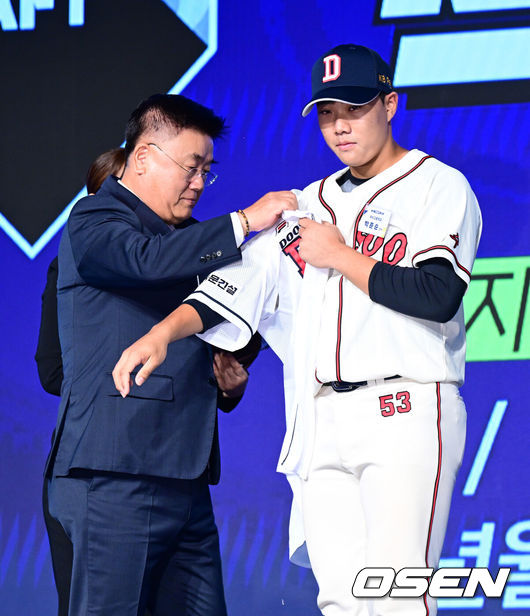 [OSEN=지형준 기자] 11일 오후 서울 잠실 롯데호텔 월드에서 2025 KBO 신인 드래프트가 열렸다.2025 KBO 신인 드래프트는 전면 드래프트 방식으로 진행된다. 지명은 1라운드부터 11라운드까지 이뤄지며, 2023년도 구단 순위의 역순인 키움-한화-삼성-롯데-KIA-두산-NC-SSG-KT-LG 순서로 실시된다.덕수고 박준순이 두산에 1라운드 지명되며 김태룡 단장에게 유니폼을 전달받고 있다. 2024.09.11 / jpnews@osen.co.kr