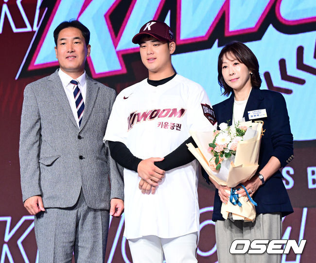 [OSEN=지형준 기자] 11일 오후 서울 잠실 롯데호텔 월드에서 2025 KBO 신인 드래프트가 열렸다.2025 KBO 신인 드래프트는 전면 드래프트 방식으로 진행된다. 지명은 1라운드부터 11라운드까지 이뤄지며, 2023년도 구단 순위의 역순인 키움-한화-삼성-롯데-KIA-두산-NC-SSG-KT-LG 순서로 실시된다.덕수고 정현우가 전체 1순위로 키움에 지명되며 고형욱 단장, 어머니와 포즈를 취하고 있다. 2024.09.11 / jpnews@osen.co.kr