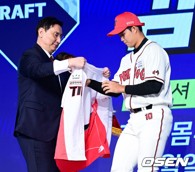 [OSEN=지형준 기자] 11일 오후 서울 잠실 롯데호텔 월드에서 2025 KBO 신인 드래프트가 열렸다.2025 KBO 신인 드래프트는 전면 드래프트 방식으로 진행된다. 지명은 1라운드부터 11라운드까지 이뤄지며, 2023년도 구단 순위의 역순인 키움-한화-삼성-롯데-KIA-두산-NC-SSG-KT-LG 순서로 실시된다.덕수고 김태형이 KIA에 1라운드 지명되며 심재학 단장이 유니폼을 전달하고 있다. 2024.09.11 / jpnews@osen.co.kr