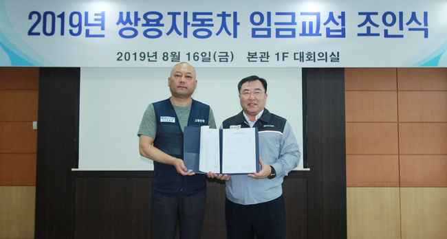 쌍용자동차 예병태 대표이사(오른쪽)와 정일권 노동조합위원장이 임금협상 합의서에 서명한 뒤 카메라 앞에 섰다.