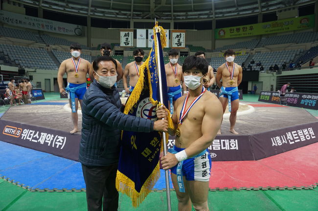 1일 제57회 대통령기전국장사씨름대회 대학부 단체전에서 우승한 경남대학교 최원준(오른쪽)이 안윤효 안동시체육회 회장(왼쪽)에게 우승기를 전달받고 있다. ⓒ 대한씨름협회