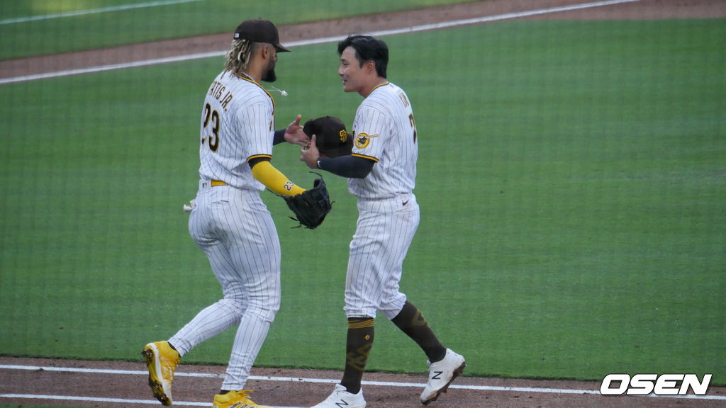 [OSEN=샌디에이고, 이사부 통신원] 샌디에이고의 김하성이 4일(한국시간) 펫코 파크에서 열린 애리조나와의 경기 1회를 마친 뒤 페르난도 타티스 주니어로부터 모자와 글러브를 전달받고 있다. /lsboo@osen.co.kr