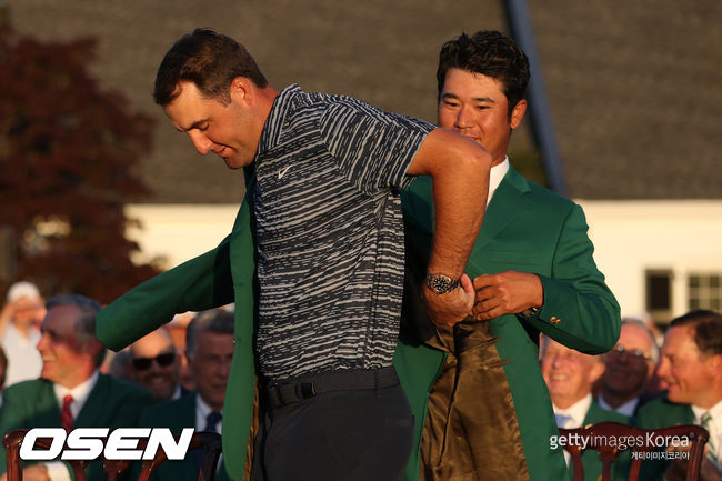 스코티 셰플러가 지난 해 우승자 마쓰야마의 도움을 받으며 그린 재킷을 입고 있다.