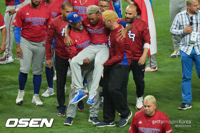 [사진] 푸에르토리코 투수 에드윈 디아즈가 세리머니를 하다 무릎 부상을 당한 뒤 코치와 트레이너에게 들린 채 그라운드를 나오고 있다. ⓒGettyimages(무단전재 및 재배포 금지)