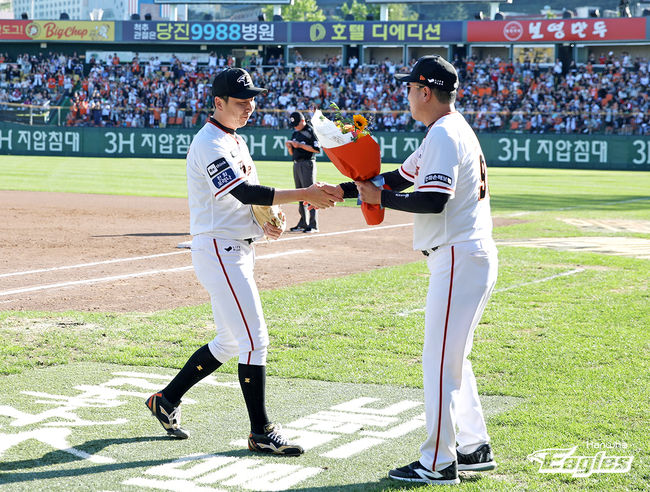 한화 정우람이 KBO리그 최초로 투수 1000경기 출장 기록을 세운 뒤 최원호 감독에게 축하 꽃다발을 받고 있다. /한화 이글스 제공