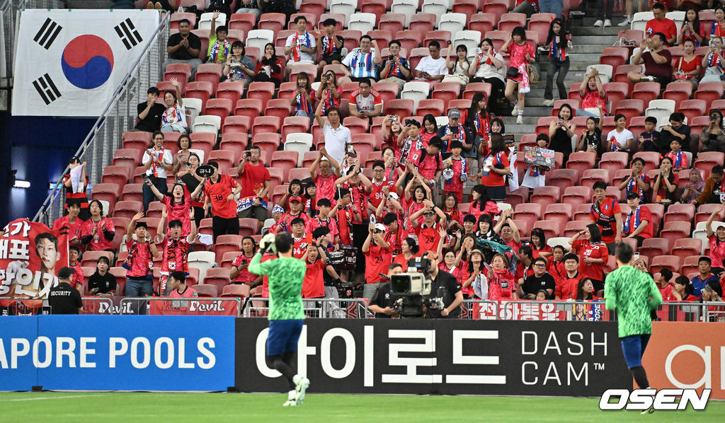 김도훈 임시감독이 이끄는 대한민국과 싱가포르의 2026 FIFA 북중미 월드컵 아시아 2차 예선 C조 5차전이 6일(한국시간) 오후 9시 싱가포르 칼랑에 위치한 싱가포르 더 내셔널 스타디움에서 열렸다.각 조 1・2위에 3차 예선 진출 자격이 주어지는 가운데 한국은 싱가포르와 5차전에서 비기기만 해도 11일 중국과 6차전 경기 결과와 상관없이 3차 예선행을 확정한다. 심지어 5차전에서 한국이 패해도 태국이 승점을 챙기지 못한다면 3차 예선으로 향할 수 있다.경기에 앞서 대한민국 응원단이 선수들에게 박수를 보내고 있다. 2024.06.06 /cej@osen.co.kr
