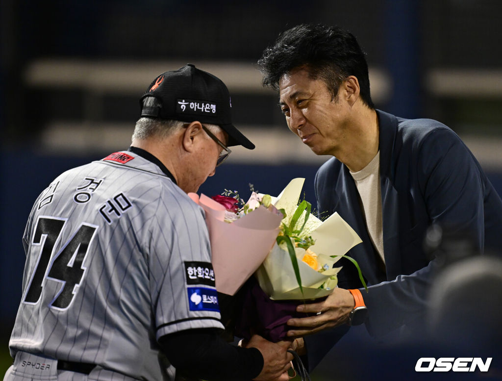 명장이 돌아왔다. 프로야구 한화 이글스 김경문 감독이 4번의 도전 끝 사령탑 통산 900승 대업을 달성했다. 한화 이글스는 11일 서울 잠실구장에서 열린 2024 신한 SOL뱅크 KBO리그 두산 베어스와의 시즌 7차전에서 6-1로 승리했다. 경기 종료 후 한화 손혁 단장이 김경문 감독에게 꽃다발을 전달하고 있다. 2024.06.11 / ksl0919@osen.co.kr