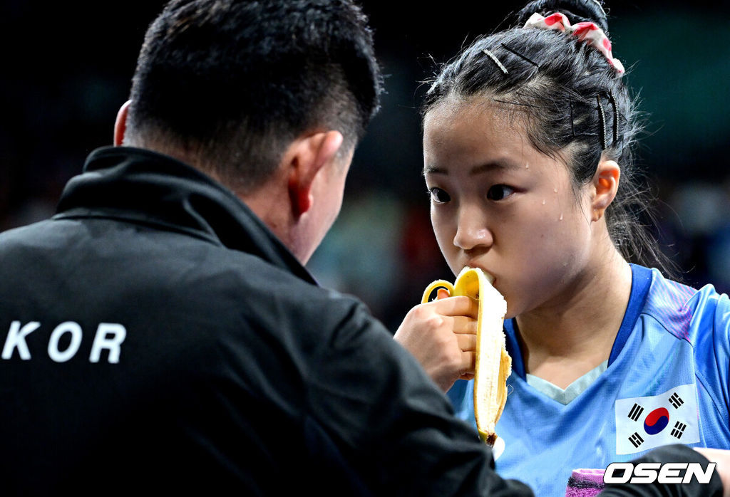 1일 (한국시간) 프랑스 파리 사우스 파리 아레나 4에서 ‘2024 파리올림픽’ 탁구 여자 단식 8강 한국 신유빈과 일본 히라노 미우의 경기가 열렸다. 신유빈은 히라노를 상대로 7게임까지 가는 접전 끝에 4-3으로 이겼다. 신유빈은 3게임까지 가져오며 상승세를 이어갔다. 하지만 히라노의 기세도 만만치 않았다. 4게임부터 3게임 연속 상대를 압도했다. 7게임 들어 손에 땀을 쥐게 하는 접전 끝에 마지막에 웃었다. 신유빈이 작전 타임 때 바나나를 먹으며 오광헌 감독과 대화를 나누고 있다. 2024.08.01 / dreamer@osen.co.kr