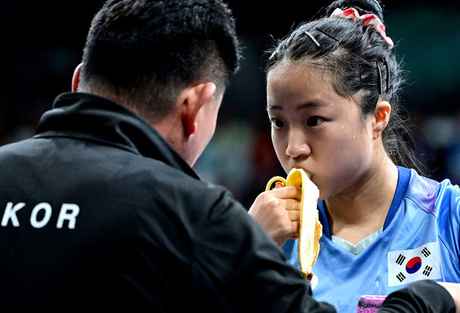 1일 (한국시간) 프랑스 파리 사우스 파리 아레나 4에서 ‘2024 파리올림픽’ 탁구 여자 단식 8강 한국 신유빈과 일본 히라노 미우의 경기가 열렸다. 신유빈은 히라노를 상대로 7게임까지 가는 접전 끝에 4-3으로 이겼다. 신유빈은 3게임까지 가져오며 상승세를 이어갔다. 하지만 히라노의 기세도 만만치 않았다. 4게임부터 3게임 연속 상대를 압도했다. 7게임 들어 손에 땀을 쥐게 하는 접전 끝에 마지막에 웃었다. 신유빈이 작전 타임 때 바나나를 먹으며 오광헌 감독과 대화를 나누고 있다. 2024.08.01 / dreamer@osen.co.kr