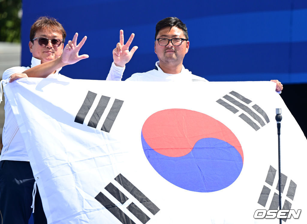 4일(한국시간) 프랑스 파리 레쟁발리드에서 ‘2024 파리올림픽’ 양궁 남자 리커브 개인 금메달결정전 한국 김우진과 미국 브래들리 엘리슨의 경기가 열렸다.김우진은 마지막 슛오프 끝에 금메달을 거머쥐었다.김우진이 박성수 감독과 함게 태극기를 들고 포즈를 취하고 있다. 2024.08.04 / dreamer@osen.co.kr