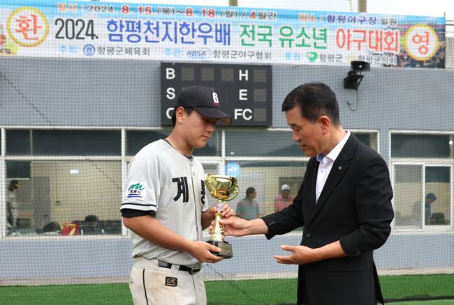 18일 전남 함평군 함평야구장에서 열린 ‘2024 함평천지한우배 전국 유소년 야구대회’ 주니어부에서 우승을 차지한 계룡퓨처스U-15야구단 김민제 선수가 선수단 대표로 함평군야구협회장에게 우승 트로피를 전달 받고 있다. /계룡퓨처스U-15 제공