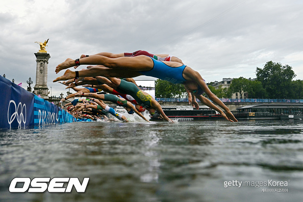 Athletes compete in the swimming race in the Seine during the women's individual triathlon at the Paris 2024 Olympic Games in central Paris on July 31, 2024. (Photo by MARTIN BUREAU / POOL / AFP)