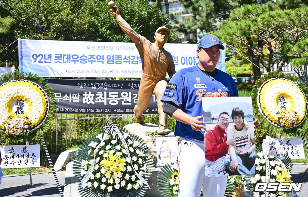 투혼, 헌신, 희생, 도전의 아이콘 불멸의 무쇠팔 故 최동원 감독 13주기 추모행사가 14일 부산 사직야구장 최동원 동상 앞에서 열렸다.1984 한국시리즈에서 혼자 4승을 따내 팀을 창단 첫 우승으로 이끌며 롯데 자이언츠 최초 영구 결번(11번)으로 지정된 선수이다.한화 류현진이 故 최동원 감독 동상 앞에서 헌화를 마치고 신인시정 최동원 감독과 함께 찍은 사진을 들고 기념촬영을 하고 있다. 2024.09.14 / foto0307@osen.co.kr