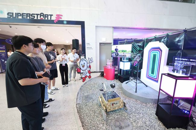 슈퍼스타트 데이 2025에서 LG 직원들이 LG의 카메라 모듈, 배터리 셀, 통신 모듈용 안테나가 탑재된 무인탐사연구소의 달 탐사 로버에 대한 설명을 듣고있다.