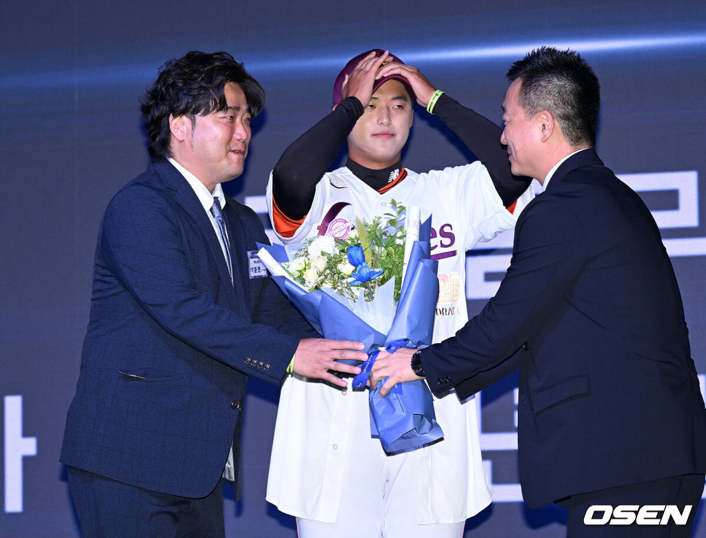 17일 오후 7일 오후 서울 롯데호텔 월드에서 ‘2026 KBO 신인 드래프트’가 열렸다.이번 드래프트는 전면 드래프트 방식으로 총 11라운드에 걸쳐 진행된다. 대상자는 총 1천261명으로, 고등학교 졸업 예정자 930명, 대학교 졸업 예정자 216명, 얼리 드래프트 신청자 51명, 해외 아마추어·프로 출신 선수 19명이다. 이 중 최대 110명이 KBO 10개 구단의 부름을 받게 된다.키움에 지명된 북일고 박준현의 아버지 박석민 전 코치가 꽃다발을 받고 있다. 2025.09.17 /sunday@osen.co.kr