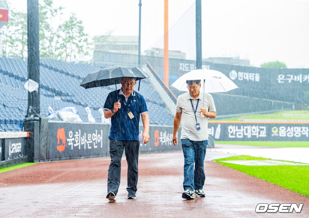 28일 오후 대전 한화생명볼파크에서 2025 신한 SOL Bank KBO리그 한화 이글스와 LG 트윈스의 경기가 열릴 예정이지만 그라운드에 비가 내리고 있다.이날 새벽부터 대전 지역에 내린 비가 오전에도 멈추지 않고 있다. 오전 11시 기준으로 시간당 6.8mm 적잖은 강수량을 보이고 있다. 내야에 대형 방수포를 깔았지만 외야와 나머지 그라운드는 빗물로 젖었다.박종훈 감독관(왼쪽)이 그라운드 상태를 보고 있다. 2025.09.28 /rumi@osen.co.kr