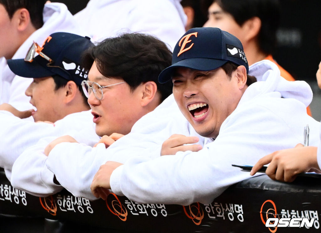 프로야구 한화 이글스가 첫 판을 승리하고, 한국시리즈 진출 확률 76.5%를 잡았다. 한화는 18일 대전 한화생명볼파크에서 열린 2025 KBO리그 플레이오프(5전 3선승제) 1차전 삼성 라이온즈와 경기에서 9-8 재역전 승리를 거뒀다. 예상과 달리 난타전이었고, 한화는 15안타를 몰아쳤다. 선발 폰세는 6이닝 7피안타(1피홈런) 1볼넷 8탈삼진 6실점(5자책)으로 부진했으나 승리 투수가 됐다. 문동주가 7회 구원투수로 등판해 2이닝 1피안타 4탈삼진 무실점으로 잘 던졌다. 마무리 김서현은 9회 등판해 홈런 등 2점을 허용하고 교체됐다. 김범수가 세이브를 기록했다. 한화 류현진이 더그아웃에서 경기를 지켜보며 미소짓고 있다. 2025.10.18 /jpnews@osen.co.kr