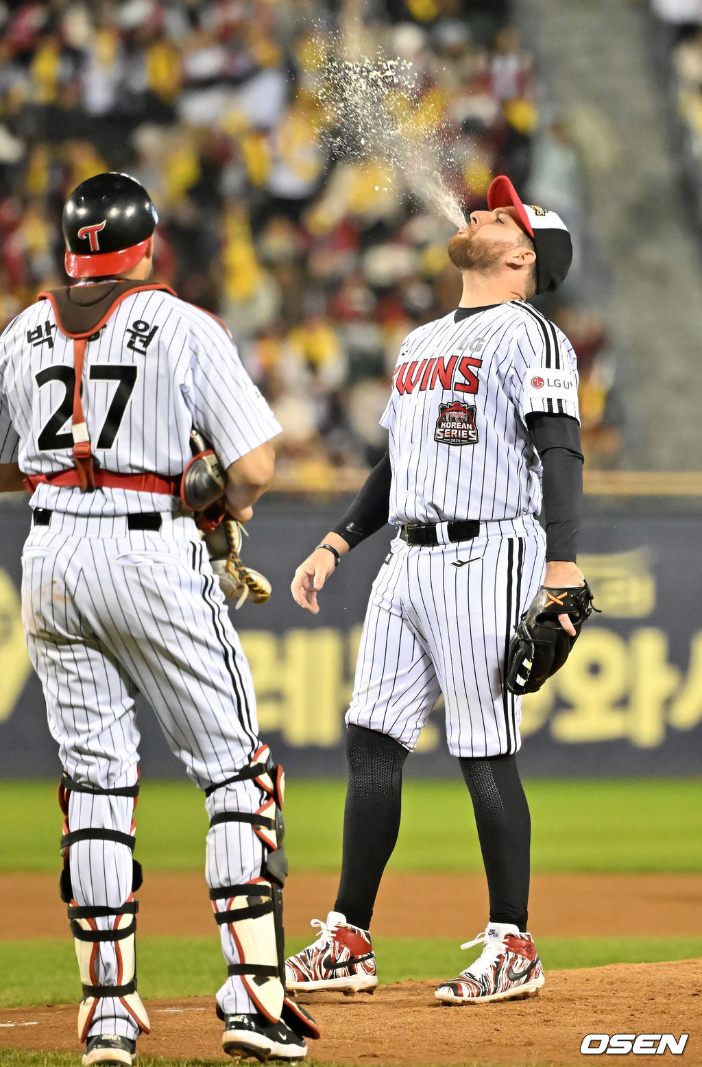 팬들을 위한 이벤트 경기에서 투수로 나선 LG 오스틴이 마운드 위에서 투수코치에게 맥주를 받아 마신 후 다시 뿜어내고 있다. 