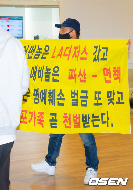 [OSEN=인천공항, 민경훈 기자] 미국프로야구 메이저리그(MLB) LA 다저스의 김혜성이 6일 오후 인천국제공항을 통해 귀국했다.김혜성은 메이저리그 진출 첫 해 우승반지를 거머쥐는 영광을 누렸다. 한국인 메이저리거 야수로는 역대 최초로 월드시리즈 우승반지를 차지한 김혜성은 올해 71경기 출전, 타율 0.280(161타수 45안타), 3홈런 17타점 19득점, 13도루(1실패), 출루율 0.314 장타율 0.385, OPS 0.699의 기록으로 정규시즌을 마무리했다.김혜성이 입국장 앞에서 인터뷰를 할때 한 남성이 비난 현수막을 펼치고 있다. 2025.11.06 /rumi@osen.co.kr