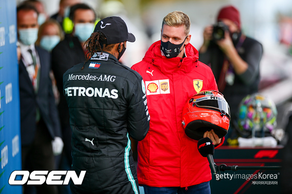 NUERBURG, GERMANY - OCTOBER 11: Mick Schumacher of Germany and Ferrari presents Lewis Hamilton of Mercedes and Great Britain  with his father Michael Schumacher's helmet to celebrate equalling his father's achievement of 91 wins during the F1 Eifel Grand Prix at Nuerburgring on October 11, 2020 in Nuerburg, Germany. (Photo by Peter Fox/Getty Images)