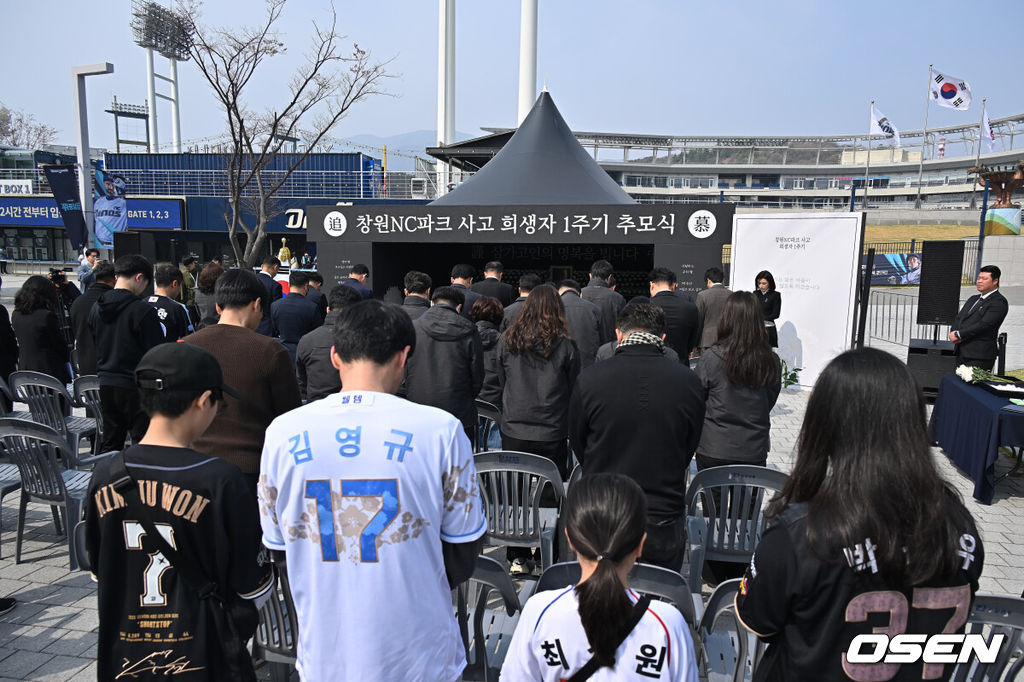 29일 창원NC파크에서 2026 신한 SOL KBO 리그 NC 다이노스와 두산 베어스의 경기가 열린다. 경남 창원시가 1년전 창원NC파크 화합의 탑 옆에서 외벽 구조물 추락 사망 사고 1주기 추모행사를 열었다. 참석한 시민과 NC 팬들이 희생자의 명복을 비는 묵념을 하고 있다. 2026.03.29 / foto0307@osen.co.kr