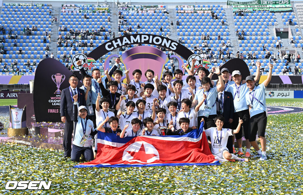 우승컵도, 100만 달러(약 15억 원) 우승 상금도 북한 내고향여자축구단 차지가 됐다. 논란 속 한국에서 열린 결승전에서 내고향은 일본 도쿄 베르디 벨레자를 꺾고 아시아 정상에 올랐다. 경기장 분위기 역시 마지막까지 씁쓸함을 남겼다.내고향은 23일 오후 수원종합운동장에서 열린 2025-2026 아시아축구연맹(AFC) 여자 챔피언스리그(AWCL) 결승전에서 도쿄 베르디를 1-0으로 꺾고 우승을 차지했다. 이날 공식 관중은 2670명이었다.경기 종료 후 내고향여자축구단 선수단이 인공기를 펼치고 기념촬영을 하고 있다. 2026.05.23 /sunday@osen.co.kr