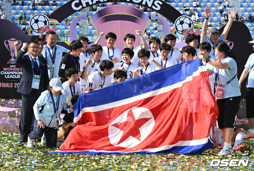 우승컵도, 100만 달러(약 15억 원) 우승 상금도 북한 내고향여자축구단 차지가 됐다. 논란 속 한국에서 열린 결승전에서 내고향은 일본 도쿄 베르디 벨레자를 꺾고 아시아 정상에 올랐다. 경기장 분위기 역시 마지막까지 씁쓸함을 남겼다.내고향은 23일 오후 수원종합운동장에서 열린 2025-2026 아시아축구연맹(AFC) 여자 챔피언스리그(AWCL) 결승전에서 도쿄 베르디를 1-0으로 꺾고 우승을 차지했다. 이날 공식 관중은 2670명이었다.경기 종료 후 내고향여자축구단 선수단이 인공기를 펼치고 기념촬영을 하고 있다. 2026.05.23 /sunday@osen.co.kr