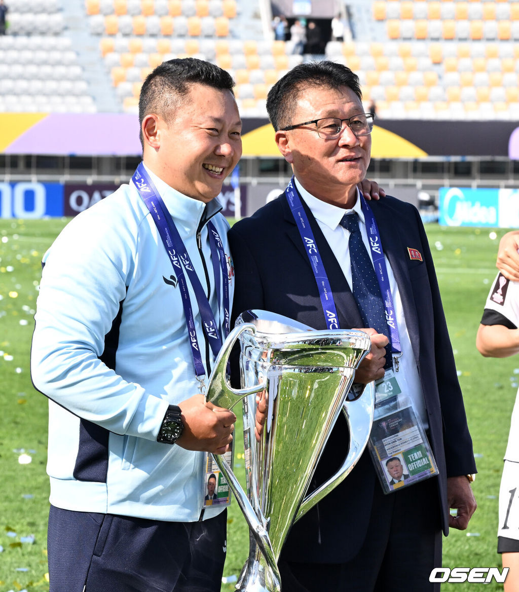 우승컵도, 100만 달러(약 15억 원) 우승 상금도 북한 내고향여자축구단 차지가 됐다. 논란 속 한국에서 열린 결승전에서 내고향은 일본 도쿄 베르디 벨레자를 꺾고 아시아 정상에 올랐다. 경기장 분위기 역시 마지막까지 씁쓸함을 남겼다.내고향은 23일 오후 수원종합운동장에서 열린 2025-2026 아시아축구연맹(AFC) 여자 챔피언스리그(AWCL) 결승전에서 도쿄 베르디를 1-0으로 꺾고 우승을 차지했다. 이날 공식 관중은 2670명이었다.경기 종료 후 내고향여자축구단 리유일 감독, 현철윤 단장이 기념촬영을 하고 있다. 2026.05.23 /sunday@osen.co.kr