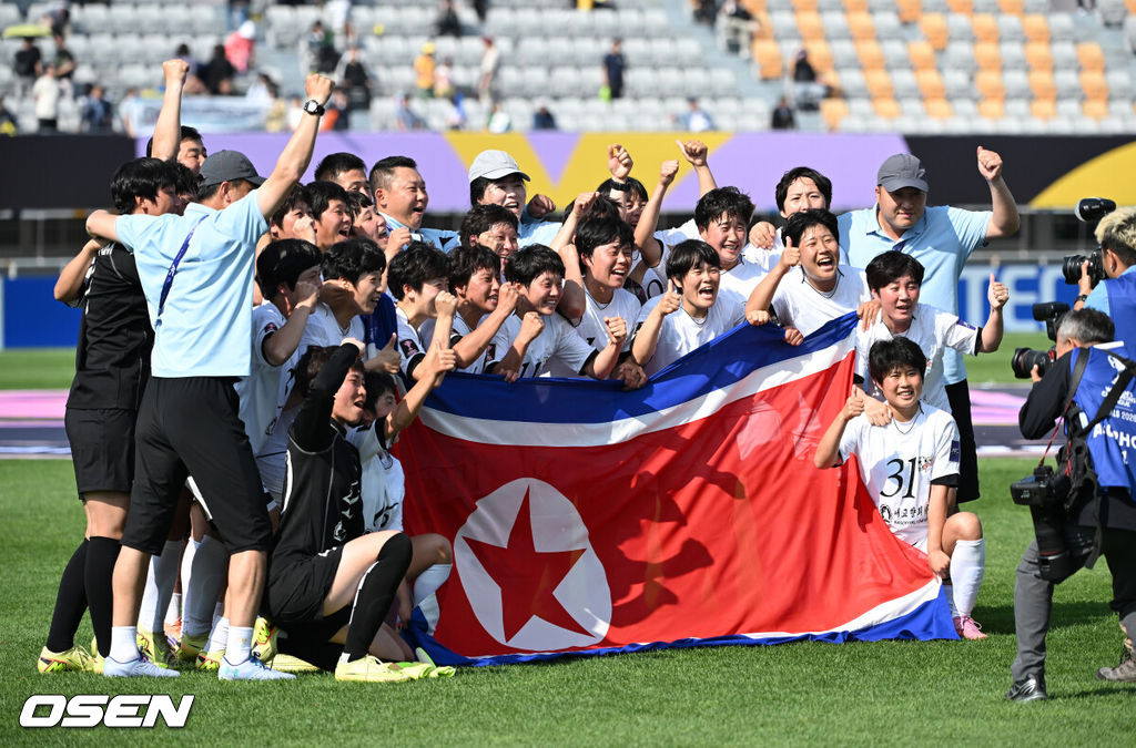 우승컵도, 100만 달러(약 15억 원) 우승 상금도 북한 내고향여자축구단 차지가 됐다. 논란 속 한국에서 열린 결승전에서 내고향은 일본 도쿄 베르디 벨레자를 꺾고 아시아 정상에 올랐다. 경기장 분위기 역시 마지막까지 씁쓸함을 남겼다.내고향은 23일 오후 수원종합운동장에서 열린 2025-2026 아시아축구연맹(AFC) 여자 챔피언스리그(AWCL) 결승전에서 도쿄 베르디를 1-0으로 꺾고 우승을 차지했다. 이날 공식 관중은 2670명이었다.경기 종료 후 내고향여자축구단 선수단이 인공기를 펼치고 기념촬영을 하고 있다. 2026.05.23 /sunday@osen.co.kr
