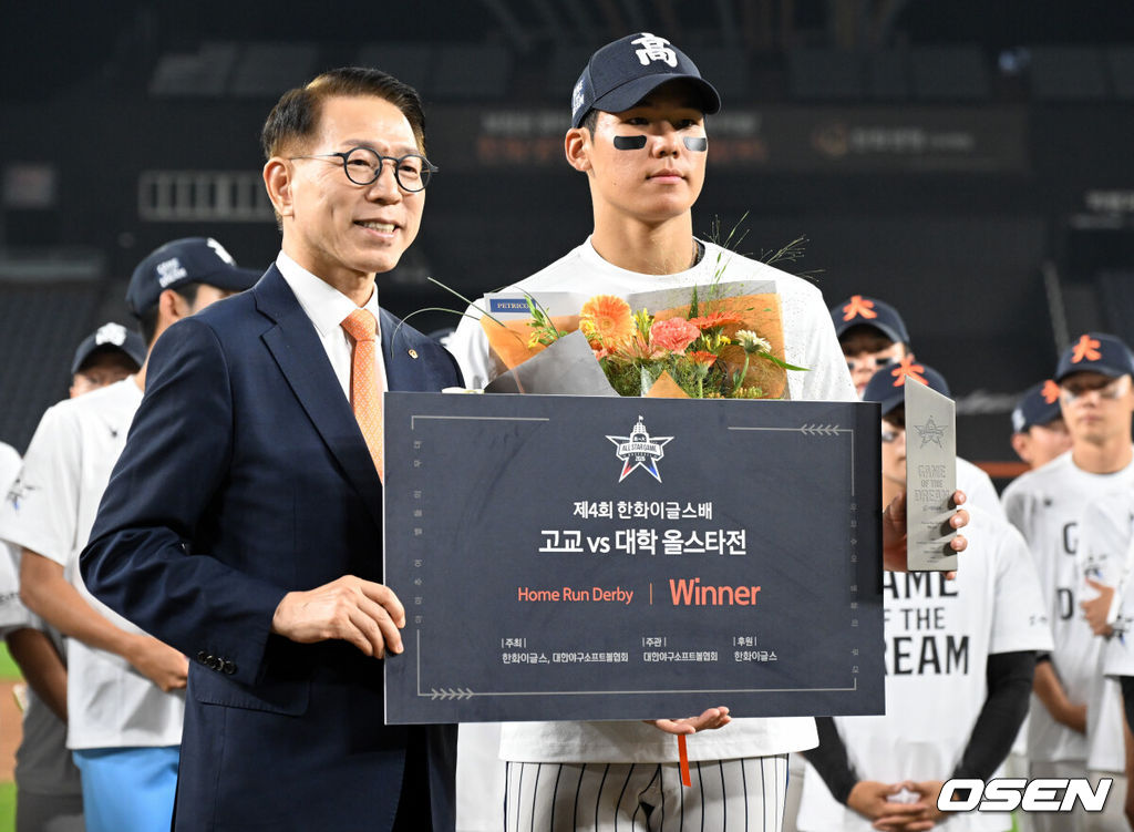 제4회 한화이글스배 고교vs대학 홈런더비 결승전이 8일 대전한화생명볼파크에서 열렸다.고교 올스타는 18세 이하 청소년 대표팀을 맡고 있는 덕수고 정윤진 감독이 지휘한다. 대학 올스타는 23세 이하 대표팀 사령탑인 성균관대 이연수 감독이 이끈다. 양 팀 선수단은 프로 10개 구단 스카우트 팀장들의 협의를 통해 선발됐다.홈런더비 우승을 차지한 서울고 김지우(오른쪽)가 한화이글스 박종태 사장과 포즈를 취하고 있다. 2026.06.08 /cej@osen.co.kr