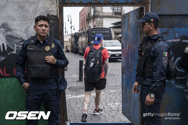 MEXICO CITY, MEXICO - MAY 18: Mexico City police guard the main square as a person wearing clothing alluding to the 2026 World Cup enters on May 18, 2026 in Mexico City, Mexico. (Photo by Cristopher Rogel Blanquet/Getty Images)<br /><br />Just days before the opening of the 2026 World Cup, the Mexico City government is maintaining security barriers due to protests by teachers from the National Coordinator of Education Workers (CNTE).