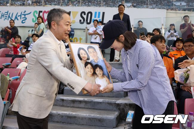 박정원 두산그룹 회장이 지난해 6월24일 '두산베어스 소방가족의 날'을 맞아 2018년 순직한 故심문규 소방장 유가족에게 AI 복원 가족사진 및 기념품 전달하고 있다.