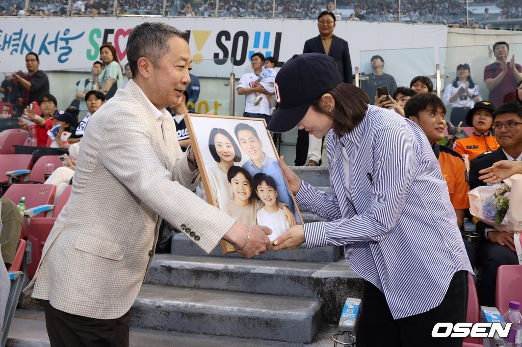 박정원 두산그룹 회장이 지난해 6월24일 '두산베어스 소방가족의 날'을 맞아 2018년 순직한 故심문규 소방장 유가족에게 AI 복원 가족사진 및 기념품 전달하고 있다.