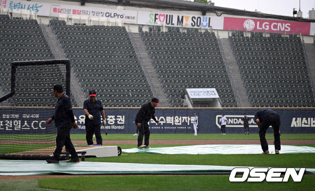 [OSEN=잠실, 조은정 기자]19일 서울 잠실야구장에서 ‘2026 신한 SOL Bank KBO리그’ LG 트윈스와 두산 베어스의 경기가 열린다.홈팀 LG는 이정용을, 방문팀 두산은 벤자민을 선발로 내세웠다.잠실구장에 갑작스런 비가 내려 그라운드 정비 요원들이 방수포를 덮고 있다. 2026.06.19 /cej@osen.co.kr