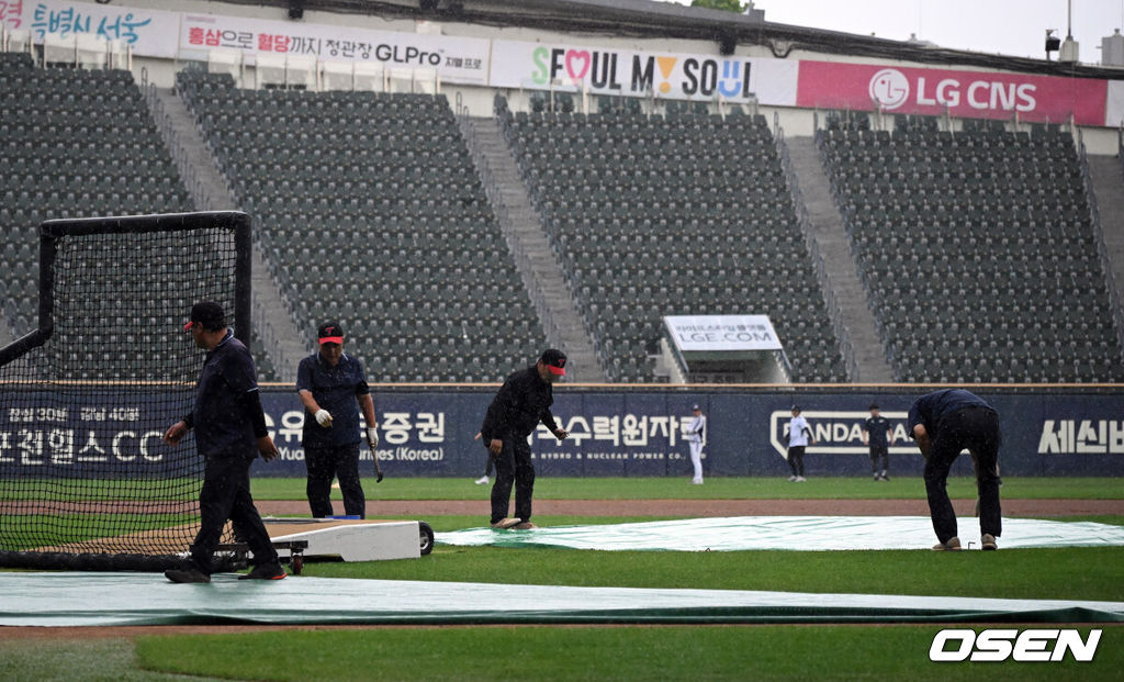 19일 서울 잠실야구장에서 ‘2026 신한 SOL Bank KBO리그’ LG 트윈스와 두산 베어스의 경기가 열린다.홈팀 LG는 이정용을, 방문팀 두산은 벤자민을 선발로 내세웠다.잠실구장에 갑작스런 비가 내려 그라운드 정비 요원들이 방수포를 덮고 있다. 2026.06.19 /cej@osen.co.kr