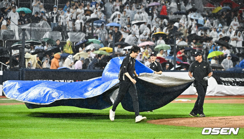 21일 오후 수원 KT위즈파크에서 열린 2026 신한 SOL KBO리그 KT 위즈와 두산 베어스의 경기가 진행됐다.이날 경기 KT는 오원석을, 두산은 벤자민을 선발투수로 내세웠다. 우천으로 경기가 중단되자 야구장 관계자들이 방수포를 덮고 있다.     2026.07.21 / soul1014@osen.co.kr