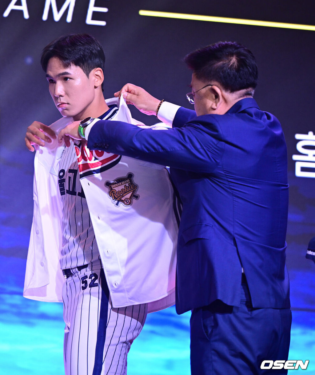 21일 오후 서울 잠실동 롯데호텔 월드 크리스탈볼룸에서 ‘2027 KBO 신인드래프트’가 열렸다. 이번 신인드래프트는 2025시즌 순위의 역순에 따라 키움 히어로즈, 두산 베어스, KIA 타이거즈, 롯데 자이언츠, KT 위즈, NC 다이노스, 삼성 라이온즈, SSG 랜더스, 한화 이글스, LG 트윈스 순서로 1라운드부터 11라운드까지 지명할 수 있다. 서울고 김지우가 전체 2번으로 두산 베어스에 지명된 뒤 유니폼을 입고 있다. 2026.09.21 / dreamer@osen.co.kr
