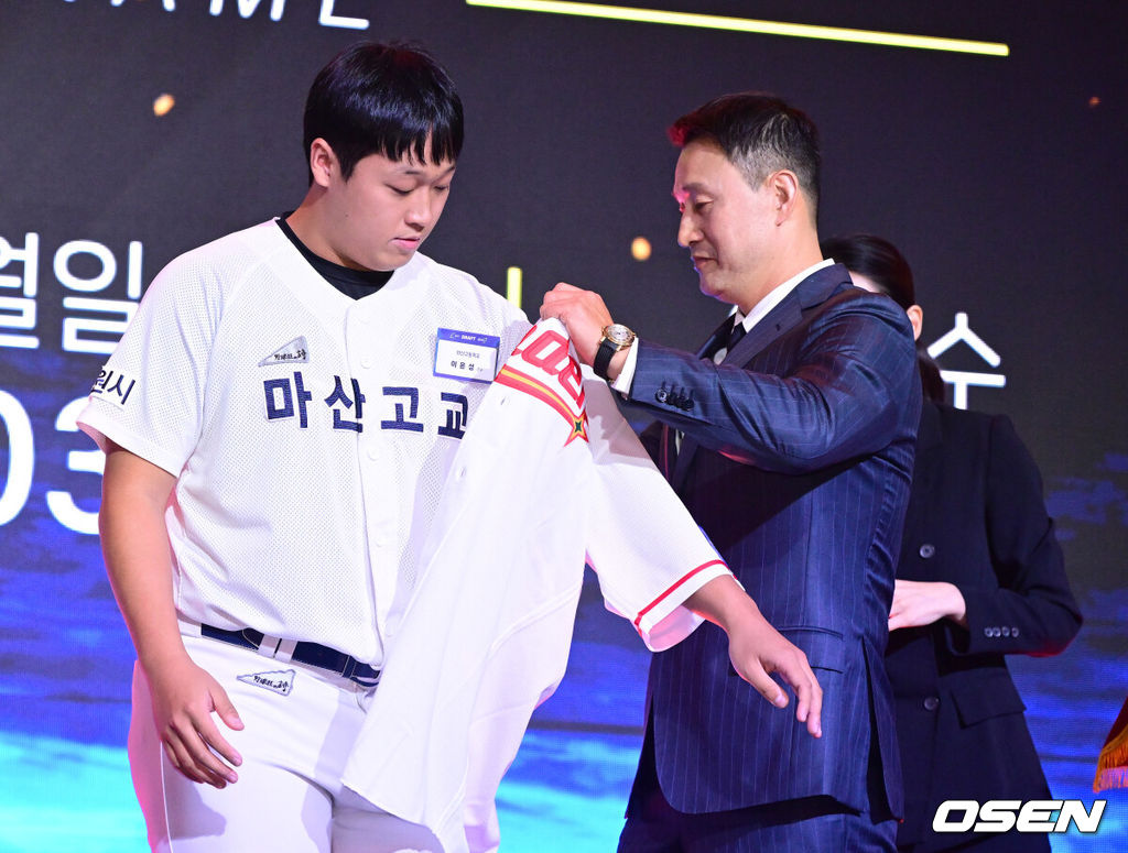 21일 오후 서울 잠실동 롯데호텔 월드 크리스탈볼룸에서 ‘2027 KBO 신인드래프트’가 열렸다. 이번 신인드래프트는 2025시즌 순위의 역순에 따라 키움 히어로즈, 두산 베어스, KIA 타이거즈, 롯데 자이언츠, KT 위즈, NC 다이노스, 삼성 라이온즈, SSG 랜더스, 한화 이글스, LG 트윈스 순서로 1라운드부터 11라운드까지 지명할 수 있다. 마산고 이윤성이 SSG 1라운드에 지명된 뒤 김재현에게 유니폼을 전달받고 있다. 2026.09.21 / dreamer@osen.co.kr