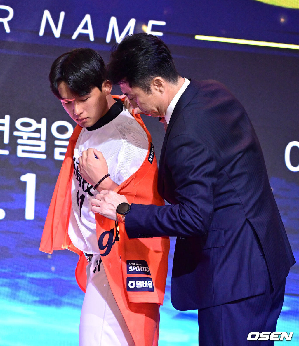 21일 오후 서울 잠실동 롯데호텔 월드 크리스탈볼룸에서 ‘2027 KBO 신인드래프트’가 열렸다. 이번 신인드래프트는 2025시즌 순위의 역순에 따라 키움 히어로즈, 두산 베어스, KIA 타이거즈, 롯데 자이언츠, KT 위즈, NC 다이노스, 삼성 라이온즈, SSG 랜더스, 한화 이글스, LG 트윈스 순서로 1라운드부터 11라운드까지 지명할 수 있다. 설악고 민주홍이 한화 1라운드에 지명된 뒤 손혁 단장에게 유니폼을 전달받고 있다. 2026.09.21 / dreamer@osen.co.kr