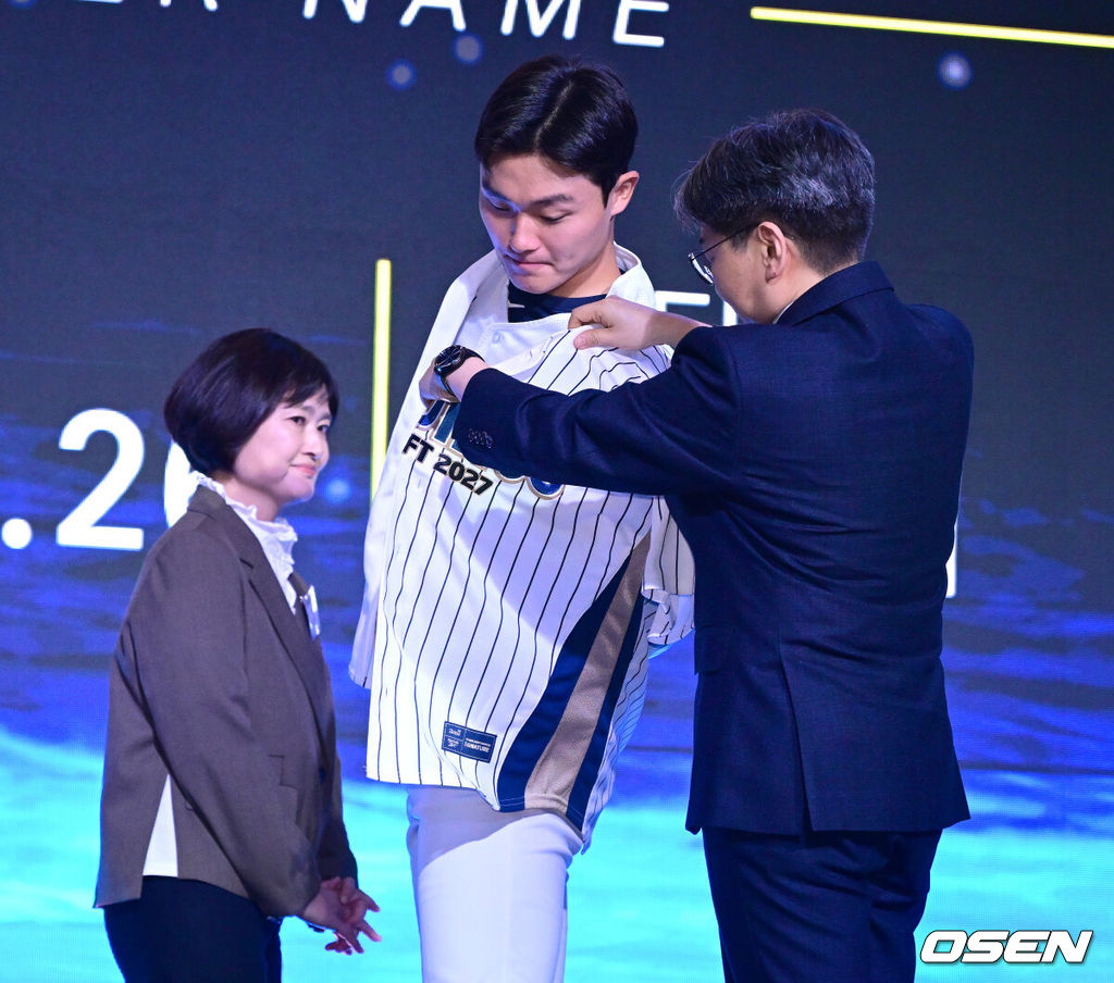 21일 오후 서울 잠실동 롯데호텔 월드 크리스탈볼룸에서 ‘2027 KBO 신인드래프트’가 열렸다. 이번 신인드래프트는 2025시즌 순위의 역순에 따라 키움 히어로즈, 두산 베어스, KIA 타이거즈, 롯데 자이언츠, KT 위즈, NC 다이노스, 삼성 라이온즈, SSG 랜더스, 한화 이글스, LG 트윈스 순서로 1라운드부터 11라운드까지 지명할 수 있다. 경남고 박보승이 NC 1라운드에 지명된 뒤 임선남 단장에게 유니폼을 전달받고 있다. 2026.09.21 / dreamer@osen.co.kr