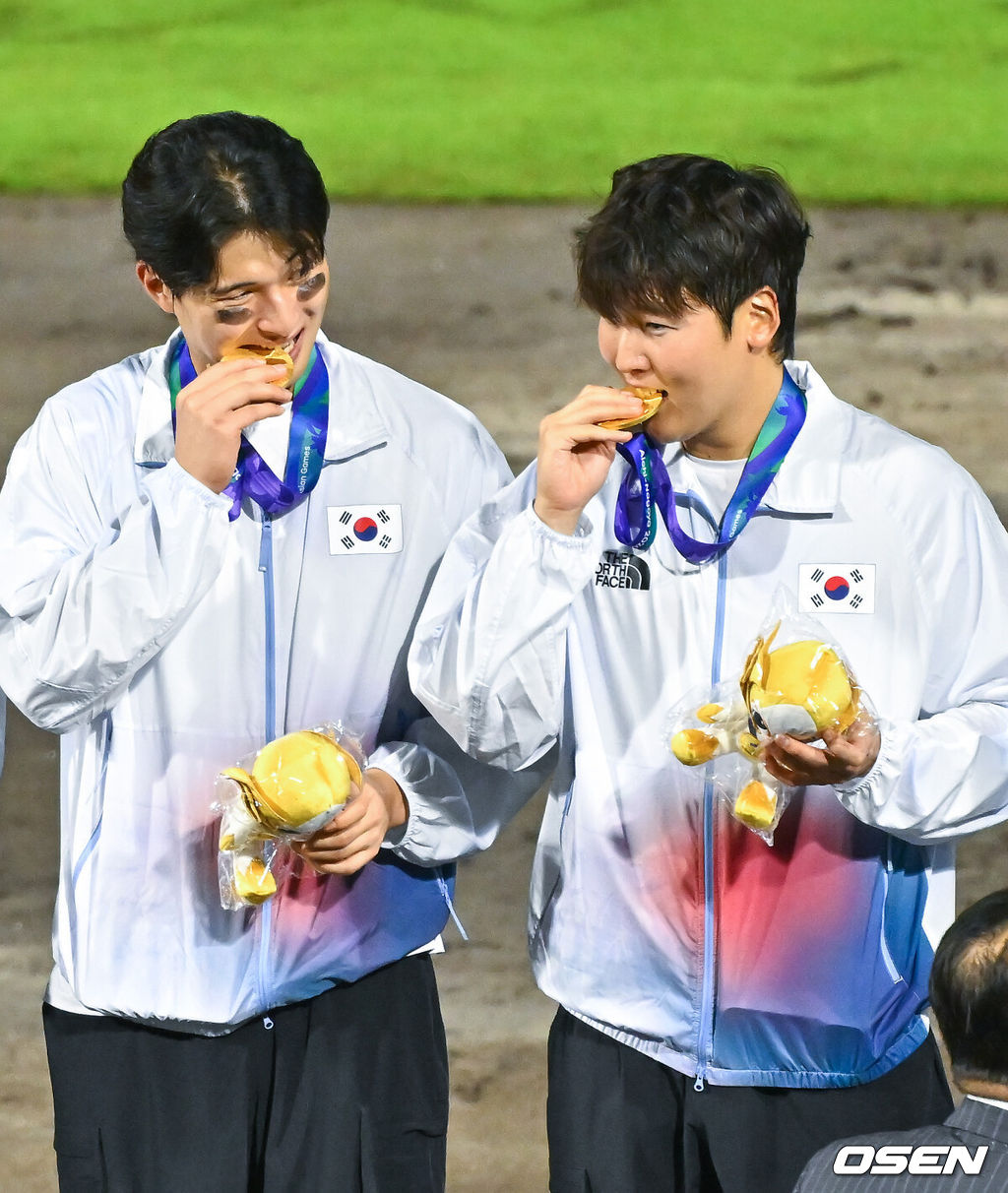 한국야구가 우여곡절 끝 아시안게임 5회 연속 금메달을 해냈다. 류지현 감독이 이끄는 한국 야구대표팀은 27일 일본 아이치현 도요하시 시민구장에서 열린 2026 아이치-나고야 아시안게임 일본과 결승전에서 3-1로 승리했다.시상식에서 윤동희와 최준용이 금메달을 깨물고 있다. 2026.09.27 / soul1014@osen.co.kr