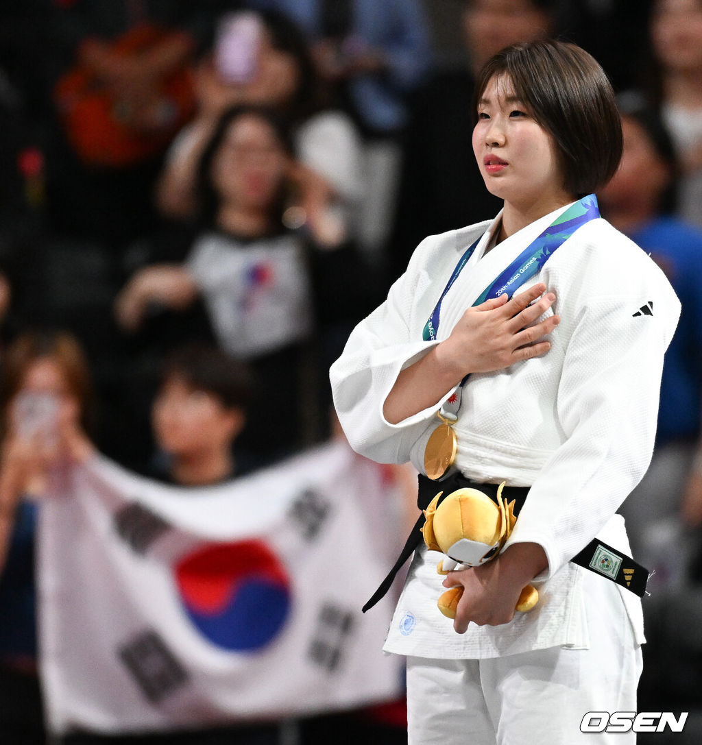 1일 일본 나고야 아이치 인터내셔널 아레나에서 2026년 아이치·나고야 아시안게임 유도 여자 57㎏급 결승 한국 허미미와 몽골 대표 테르비시 아리운자야의 경기가 진행됐다.허미미는 한국인 아버지와 일본인 어머니 사이에서 태어난 '재일교포'다. 복수국적자였지만, 2021년 '한국 선수로 뛰는 모습을 보고 싶다'는 할머니의 유언에 따라 한국 국적을 택했다.시상식에서 금메달 수상한 허미미가 태극기를 향해 국민의례를 하고 있다.  2026.10.01 / soul1014@osen.co.kr